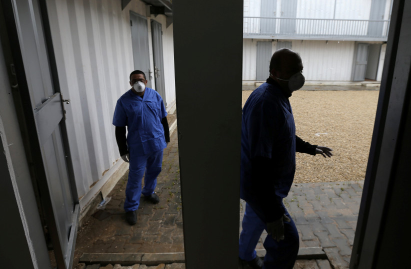 Palestinian health workers wearing protective masks walk in a quarantine zone installed by the ministry of health to test passengers returning from China for coronavirus, at Rafah border crossing in the southern Gaza Strip February 16, 2020. (photo credit: REUTERS/IBRAHEEM ABU MUSTAFA)