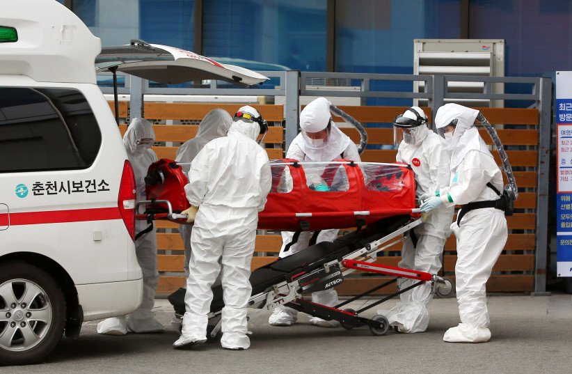 A confirmed coronavirus patient is wheeled to a hospital at Chuncheon, South Korea, February 22, 2020. (photo credit: YONHAP VIA REUTERS)