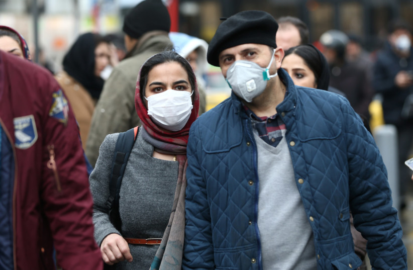 Iranian couple wearing protective masks to prevent contracting a coronavirus walk at Grand Bazaar in Tehran, Iran (photo credit: WANA NEWS AGENCY/REUTERS)