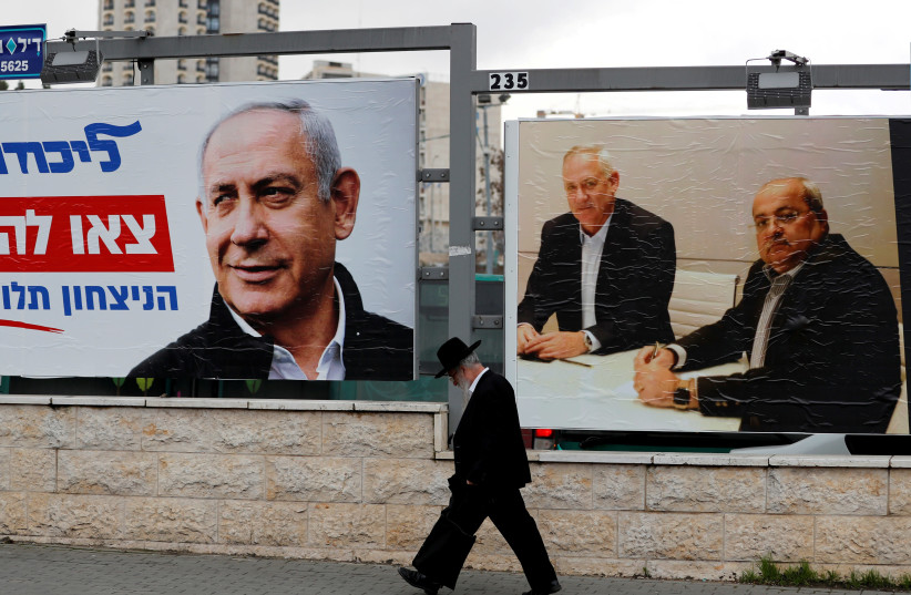 An ultra-Orthodox Jewish man walks next to Likud party election campaign banners in Jerusalem February 20, 2020. (photo credit: AMMAR AWAD / REUTERS)