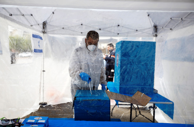 A medic in a protective suit votes in a special polling station set up by Israel's election committee so Israelis under home-quarantine, such as those who have recently travelled back to Israel from coronavirus hot spots can vote in Israel's national election, in Ashkelon, Israel March 2, 2020 (photo credit: REUTERS/AMIR COHEN)