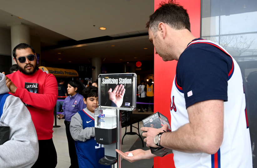 Fans use hand sanitizer as they enter Staples Center in California amid the coronavirus outbreak (photo credit: JAYNE KAMIN-ONCEA-USA TODAY SPORTS/REUTERS)