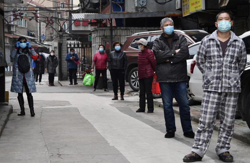Residents line up to collect vegetables purchased through group orders at a residential area in Wuhan, the epicentre of the novel coronavirus outbreak, Hubei province, China March 5, 2020. (photo credit: REUTERS/STRINGER)