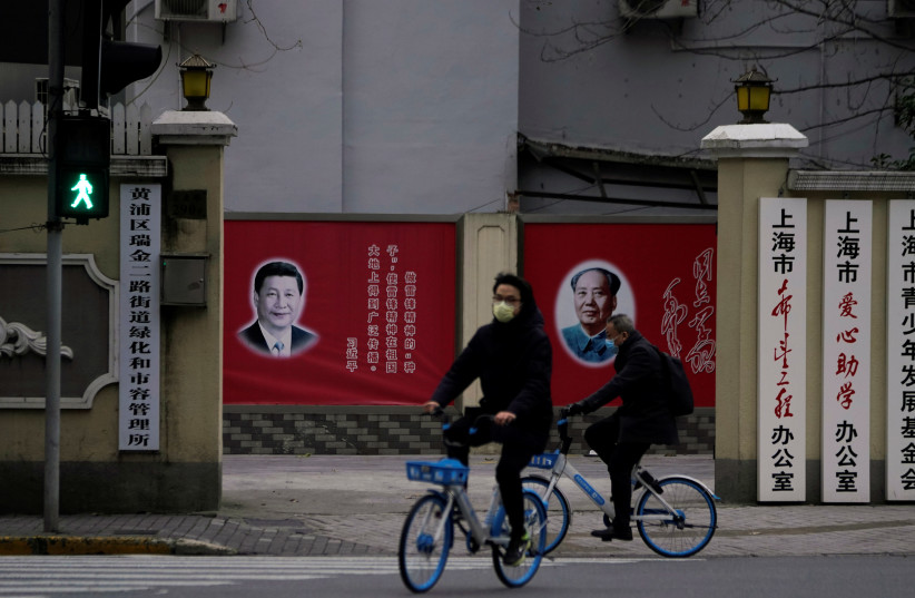 People wearing masks pass by portraits of Chinese President Xi Jinping and late Chinese chairman Mao Zedong as the country is hit by an outbreak of the novel coronavirus, on a street in Shanghai, China February 10, 2020 (photo credit: REUTERS/ALY SONG)