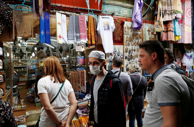 A man wears a face mask for protection releted to the coronavirus as he walks in Jerusalem's Old City March 9, 2020 (photo credit: REUTERS/RONEN ZEVULUN)