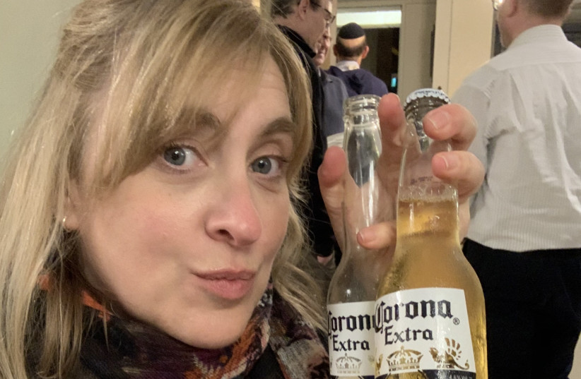 EMPLOYING BLACK humor to escape the panic, many – like Miriam Gold (pictured) – have been taking selfies with Corona bottles. The beer company could probably use our prayers as well. (photo credit: BENJY SINGER)