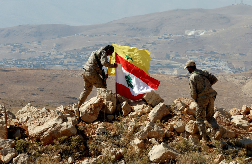 Hezbollah fighters put Lebanese and Hezbollah flags at Juroud Arsal, Syria-Lebanon border (photo credit: REUTERS)