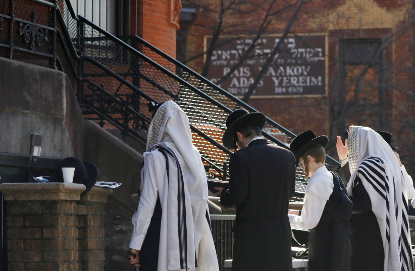 Hasidic Jewish men gather for a morning prayer outside of a synagogue, closed due to coronavirus disease (COVID-19), in South Williamsburg, Brooklyn, New York City, New York (photo credit: REUTERS)