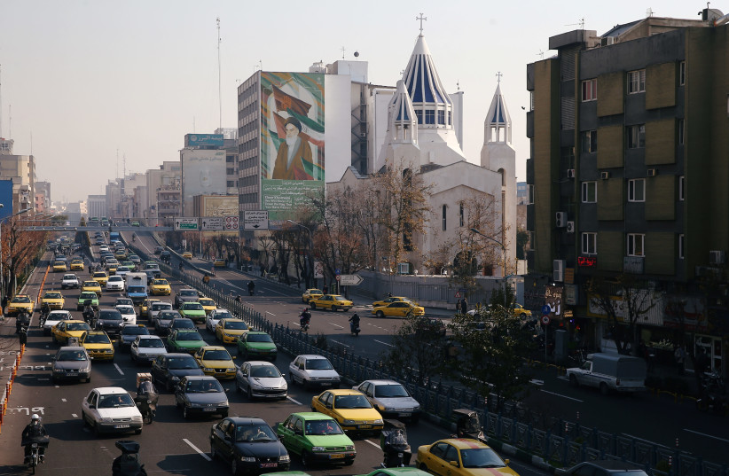 Saint Sarkis Cathedral and a building with a mural of Iran's late leader Ayatollah Ruhollah Khomeini in Tehran, Iran December 21, 2019 (photo credit: NAZANIN TABATABAEE/WANA VIA REUTERS)