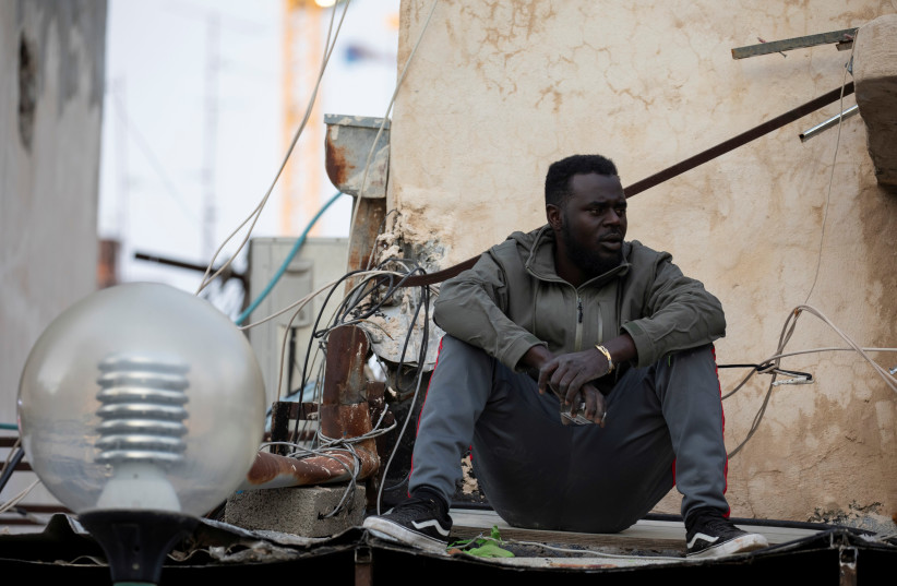 An African migrant sits near the Old Central Bus Station in south Tel Aviv, Israel February 3, 2020 (photo credit: REUTERS/AMIR COHEN)