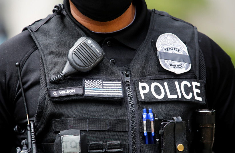 A Seattle police officer wears a "mourning band" for fallen officers over his badge, obscuring the badge number, as Seattle police guard the department headquarters downtown during a rally and march calling for a defunding of Seattle police, in Seattle, Washington, U.S. June 3, 2020 (photo credit: REUTERS/LINDSEY WASSON)