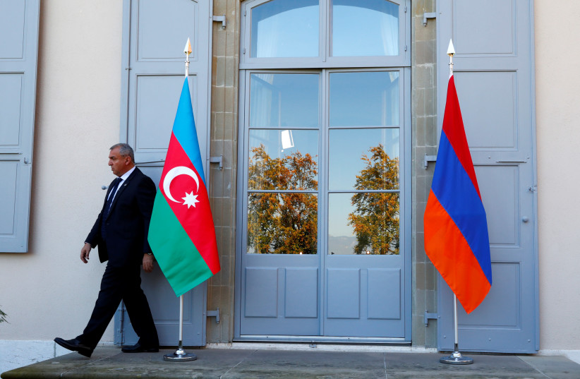 A security guard walks past an Azeri (L) and Armenian flag at the opening of talks in Geneva, Switzerland, October 16, 2017. (photo credit: REUTERS/DENIS BALIBOUSE)