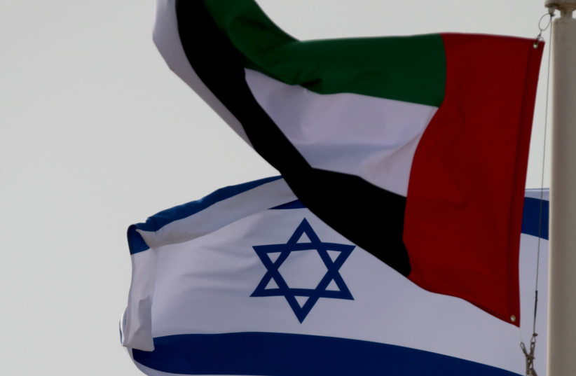 A United Arab Emirates (UAE) flag waves alongside an Israeli flag (photo credit: REUTERS/CHRISTOPHER PIKE)