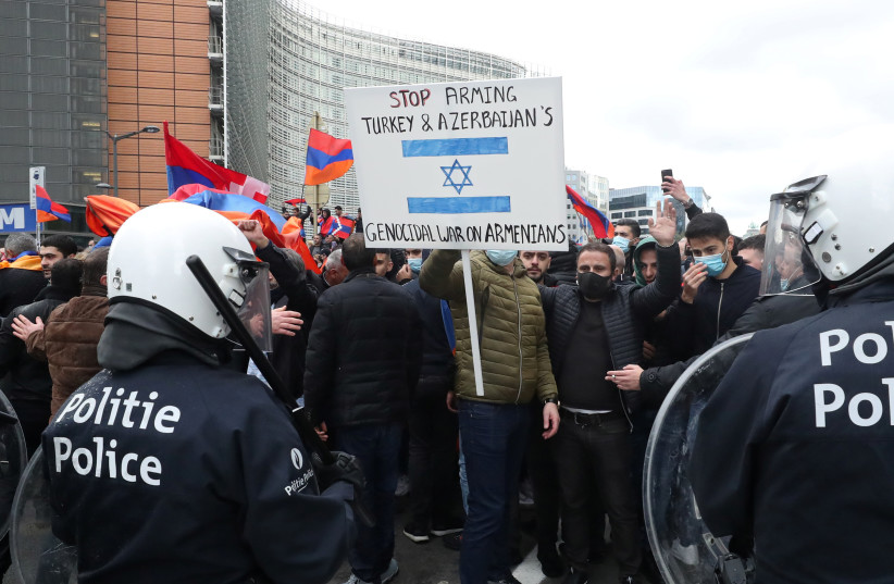 Demonstrators supporting Armenia hold a sign protesting Israel's sale of arms to Azerbaijan in the military conflict over the breakaway region of Nagorno-Karabakh, in Brussels, Belgium October 7, 2020 (photo credit: REUTERS/YVES HERMAN)