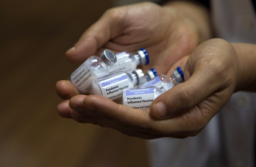 An Israeli medical worker holds vials containing a vaccine for H1N1 flu virus in Tel Aviv, 2009 (photo credit: HEIDI LEVINE/POOL/REUTERS)