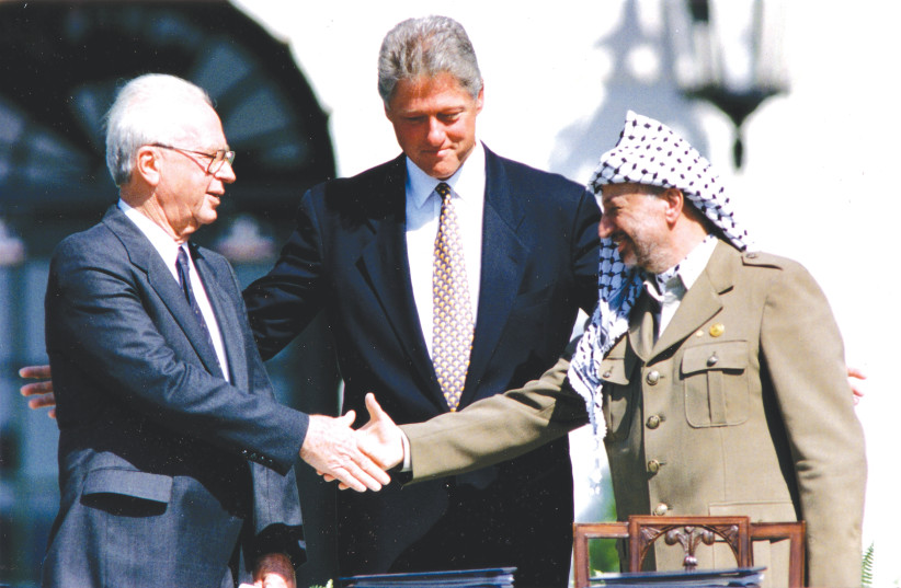 US PRESIDENT Bill Clinton watches high minister Yitzhak Rabin and PLO chairman Yasser Arafat shake palms after signing the Oslo I Accord, on the White Residence in Washington on September 13, 1993. (list credit score: GARY HERSHORN/REUTERS)