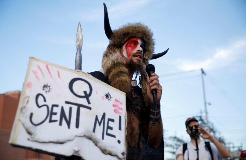 Jacob Chansley, also known as Jake Angeli, holding a sign referencing QAnon, speaks as supporters of U.S. President Donald Trump gather to protest about the early results of the 2020 presidential election (photo credit: CHENEY ORR/REUTERS)