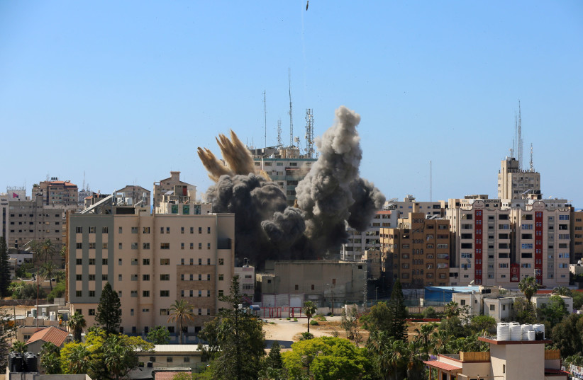 A missile falls as smoke rises near a tower housing AP, Al Jazeera offices (C) during Israeli missile strikes in Gaza city, May 15, 2021.  (photo credit: REUTERS/ASHRAF ABU AMRAH)
