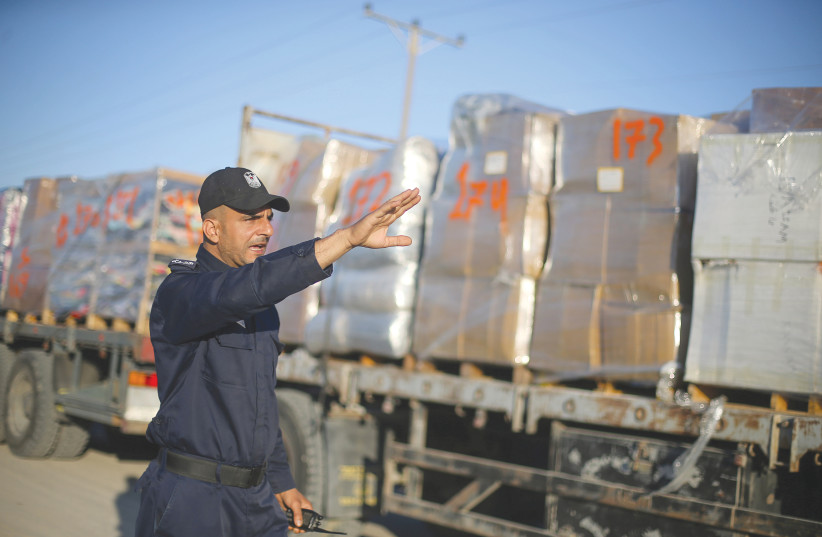 A PALESTINIAN POLICE officer gestures as he stands next to a truck carrying clothes for export at the Kerem Shalom crossing in Rafah in the southern Gaza Strip, on Monday. (photo credit: IBRAHEEM ABU MUSTAFA / REUTERS)
