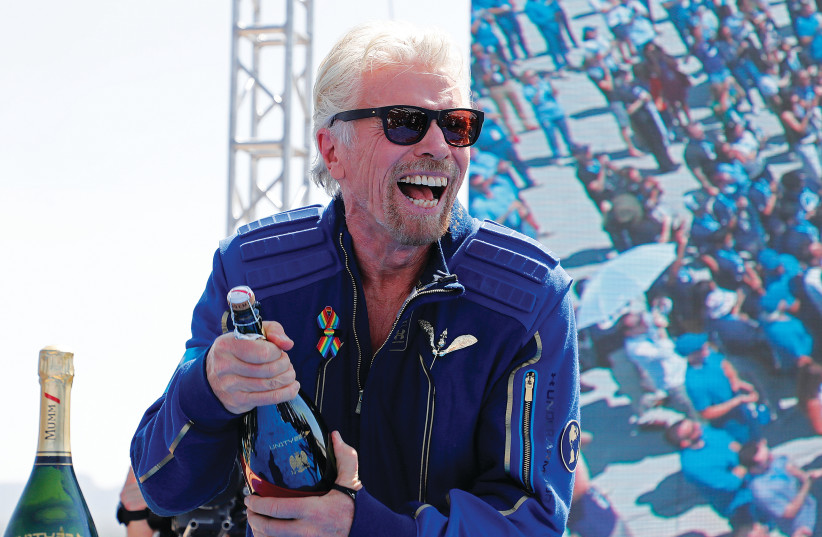 RICHARD BRANSON prepares to spray champagne after flying with a crew in Virgin Galactic’s passenger rocket plane ‘VSS Unity’ on July 11. (photo credit: JOE SKIPPER/REUTERS)