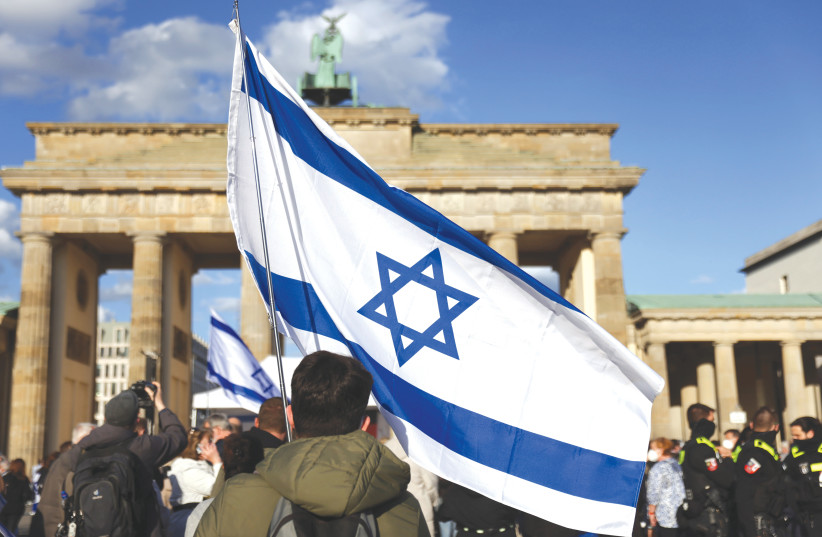 A man waves an Israeli flag during a rally against antisemitism, in front of the Brandenburg Gate in Berlin in May.  (photo credit: CHRISTIAN MANG / REUTERS)