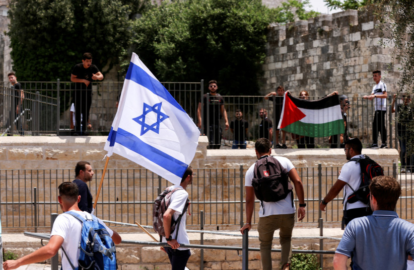  Israelis stand with an Israeli flag opposite to Palestinians with Palestinian flag next to Damascus gate to Jerusalem's Old City, on Jerusalem Day, May 29, 2022. (photo credit: AMMAR AWAD/REUTERS)