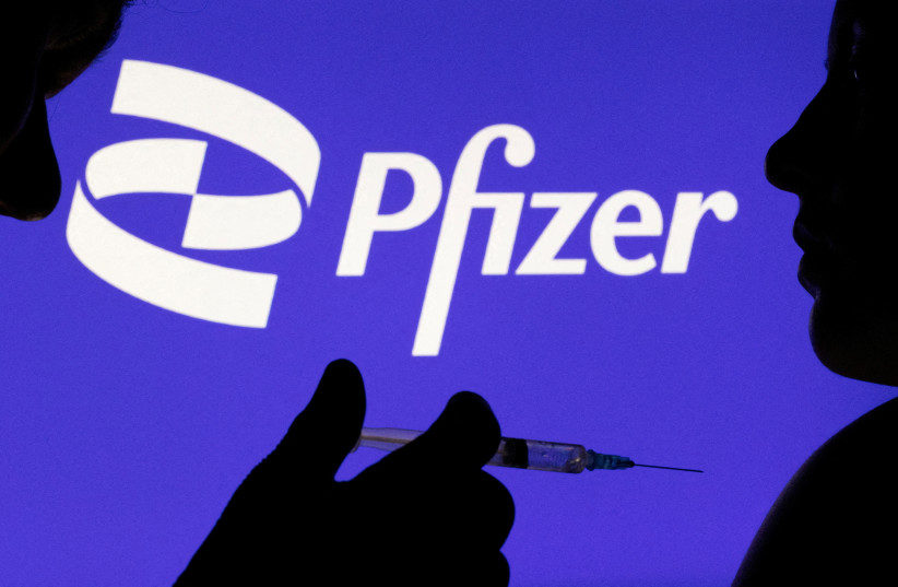  People pose with syringe with needle in front of displayed Pfizer logo in this illustration taken. (photo credit: REUTERS)