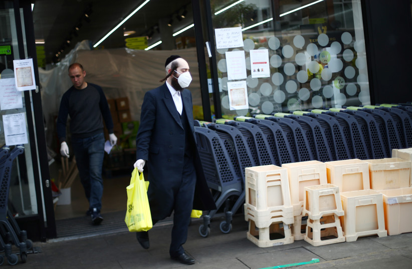  An Orthodox Jewish man wearing a protective face mask and gloves is seen outside a shop in Stamford Hill, as the spread of the coronavirus disease (COVID-19) continues, London, Britain, April 8, 2020.  (photo credit: REUTERS/HANNAH MCKAY)