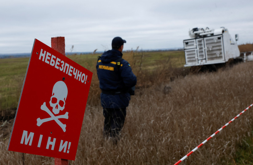  View of a mine-warning sign as a Ukrainian service member demonstrates clearing a minefield using a remote control for the Armtrac 400 demining machine, capable of clearing 2,400 square metres per hour, amid Russia's invasion, in the Kharkiv region of Ukraine October 27, 2022. (photo credit: CLODAGH KILCOYNE/REUTERS)