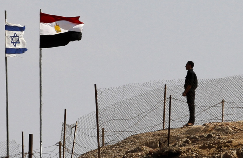  An Egyptian soldier stands near the Egyptian national flag and the Israeli flag at the Taba crossing between Egypt and Israel, about 430 km (256 miles) northeast of Cairo, October 26, 2011 (photo credit: MOHAMED ABD EL-GHANY/REUTERS)