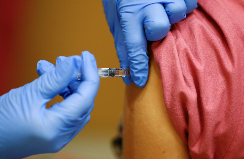  A member of the medical staff receives a flu vaccine at the department where patients suffering from the coronavirus disease (COVID-19) are treated in the Intensive Care Unit (ICU) at Havelhoehe community hospital in Berlin, Germany, October 30, 2020. (photo credit: REUTERS/FABRIZIO BENSCH)
