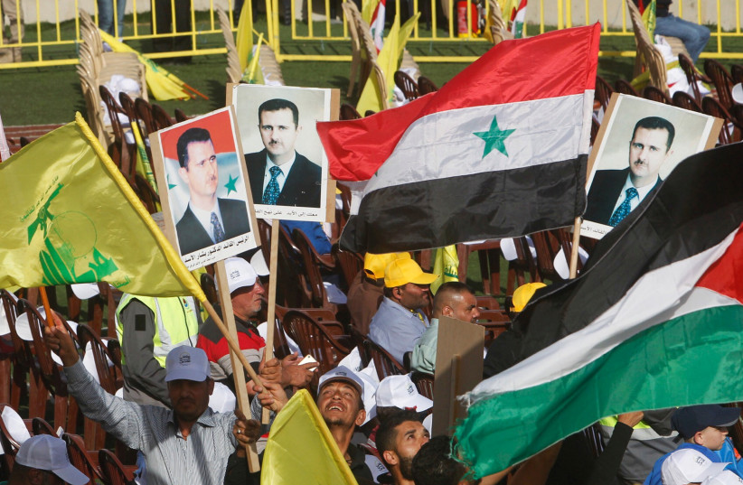  Supporters of Lebanon's Hezbollah leader Sayyed Hassan Nasrallah carry flags and pictures of Syria's President Bashar al-Assad during a rally marking al-Quds Day, (Jerusalem Day) in Maroun Al-Ras village, near the border with Israel, southern Lebanon June 8, 2018. (photo credit: REUTERS/AZIZ TAHER)