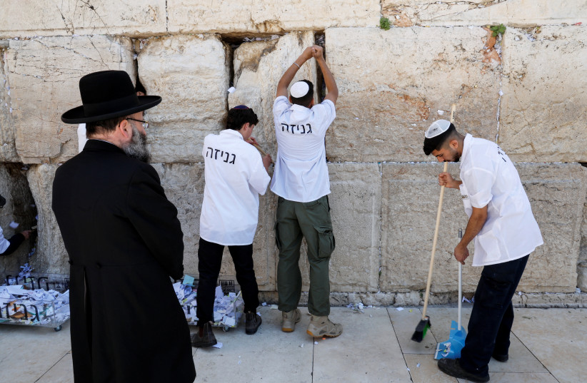  Workers remove notes from the cracks of the Western Wall to make space for new notes, as part of preparations ahead of the Jewish holiday of Passover, in Jerusalem's Old City, April 2, 2023. (photo credit: REUTERS/AMMAR AWAD)