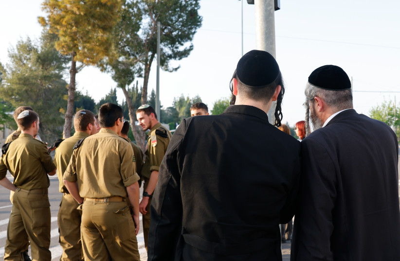  Haredi men dressed in traditional ultra-Orthodox garb stand behind a group of religious IDF soldiers (photo credit: MARC ISRAEL SELLEM/THE JERUSALEM POST)