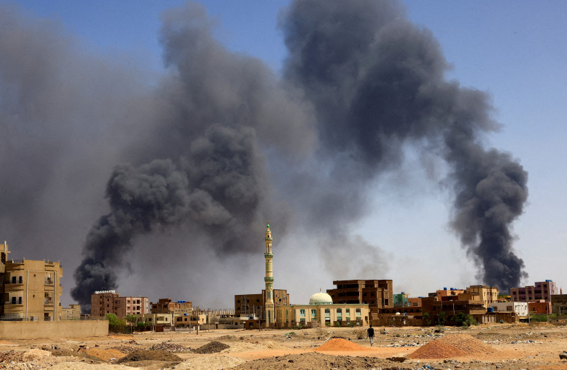  A man walks while smoke rises above buildings after aerial bombardment, during clashes between the paramilitary Rapid Support Forces and the army in Khartoum North, Sudan, May 1, 2023.  (photo credit: REUTERS/MOHAMED NURELDIN ABDALLAH)