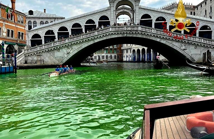 Venice's waters turn green due to an unknown substance near the Rialto Bridge, in Venice, Italy in this handout image released May 28, 2023. (photo credit: VIGILI DEL FUOCO/HANDOUT VIA REUTERS)