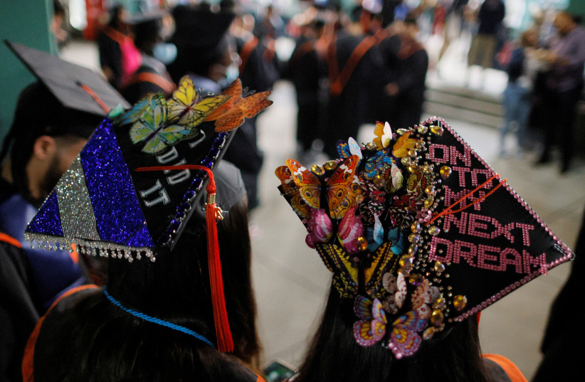 Brighton High School seniors, with the messages “I Did It” and “On To My Next Dream” on their caps, wait for their graduation ceremony being held at Fenway Park, home of Major League Baseball’s Boston Red Sox for greater safety during the coronavirus disease (COVID-19) pandemic, in US, June 15, 2021 (photo credit: BRIAN SNYDER/REUTERS)