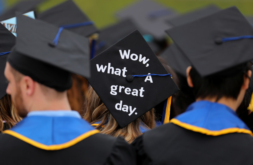 Messages and artwork are pictured on the top of the caps of graduating students during their graduation ceremony at UC San Diego in San Diego, California, US June 17, 2017.  (photo credit: MIKE BLAKE/REUTERS)
