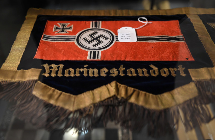 A flag with a swastika is seen in a cupboard at the auction house Hermann Historica in Munich, Germany, November 20, 2019. Several hundred Nazi objects were up for auction, amongst them Adolf Hitler's hat and one of Eva Braun's dresses (photo credit: ANDREAS GEBERT/REUTERS)