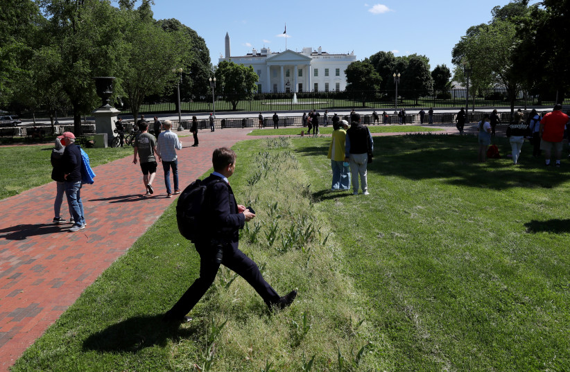  A visitor walks through an overgrown tulip bed as people walk around Lafayette Square after the fence was opened to allow public back inside the park following a closure that lasted months outside of the White House in Washington, US, May 10, 2021 (photo credit: REUTERS/LEAH MILLIS)