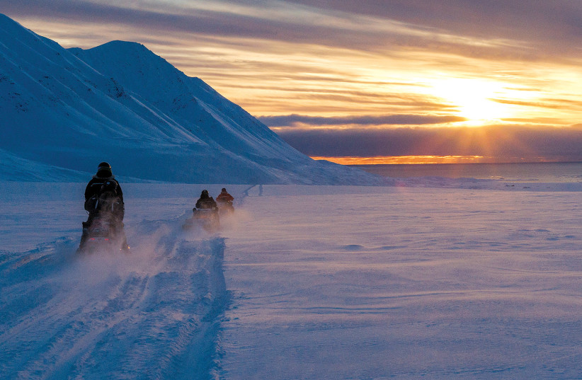  Climate change thaws the world’s northernmost research station: Scientists drive their snowmobiles across the Arctic toward Kongsfjord at sunset near Ny-Alesund, Svalbard, Norway, on April 10. (photo credit: Lisi Niesner/Reuters)