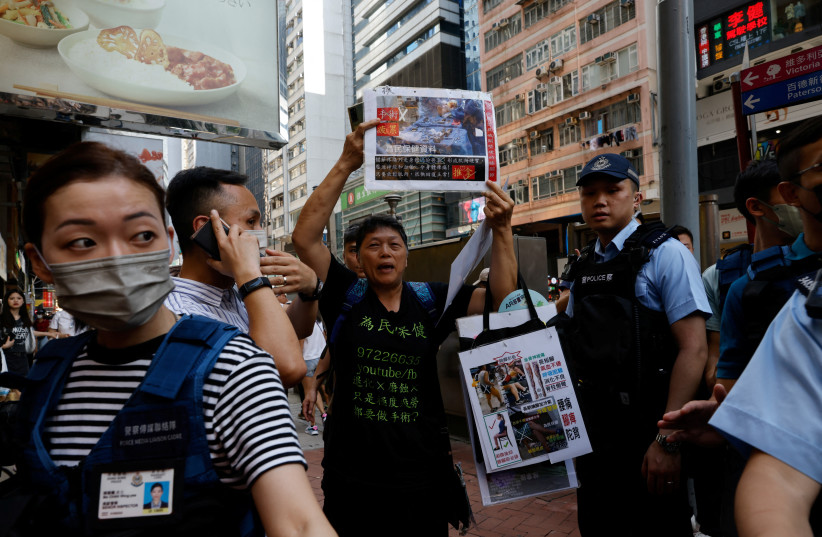  Police detain a woman who holds placards to promote knee maintenance in downtown Hong Kong on the 34th anniversary of the 1989 Beijing Tiananmen Square crackdown, near the location where the candlelight vigil is usually held, in Hong Kong, China June 4, 2023.  (photo credit: TYRONE SIU/ REUTERS)