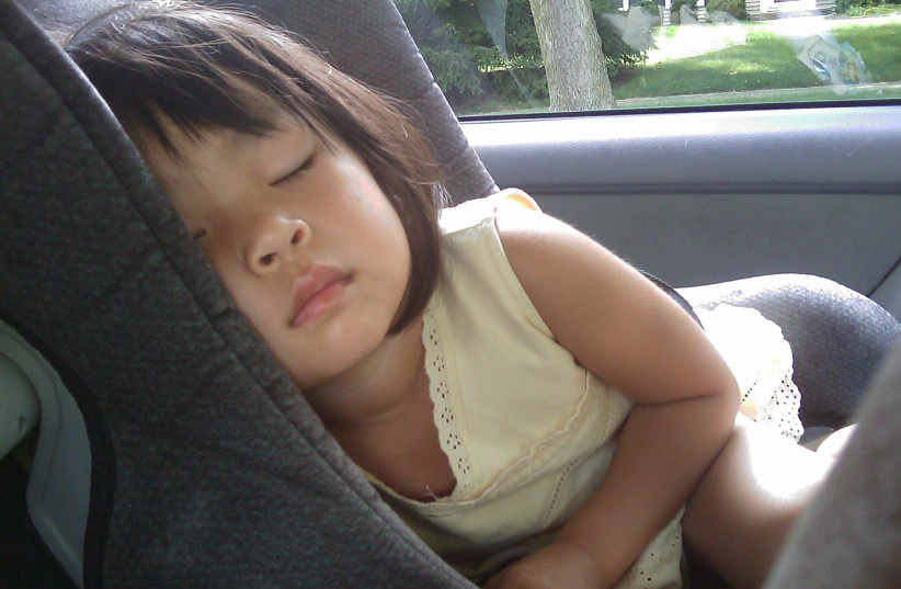  A young child is seen sleeping in a car (Illustrative). (photo credit: PXHERE)