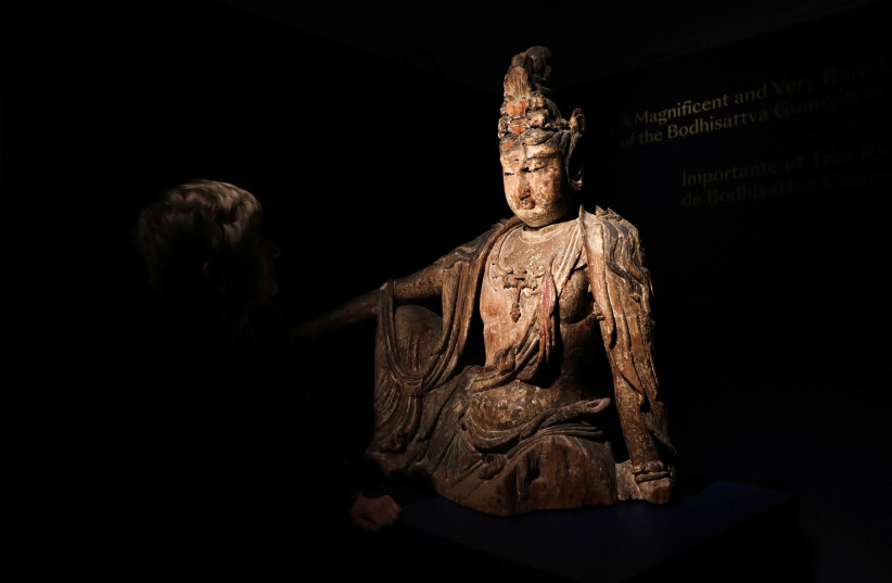  Head of Chinese Art Caroline Schulten at Bonhams auction house looks at a rare Buddha statue, believed to be from the 12th century in China, before its auction in Paris, France, June 9, 2023. (photo credit: REUTERS/Yiming Woo)