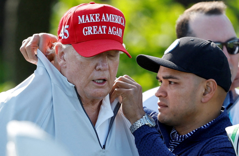 Walt Nauta, personal aide to former U.S. President Donald Trump who faces charges of being Trump's co-conspirator in the alleged mishandling of classified documents, fixes Trump's collar before a LIV Golf Pro-Am golf tournament at the Trump National Golf Club in Sterling, Virginia, U.S. May 25, 2023 (photo credit: REUTERS/JONATHAN ERNST)