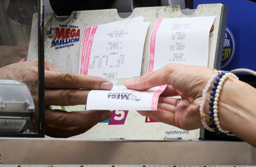  A woman buys a ticket for the Mega Millions lottery drawing at a news stand in New York City, U.S., July 26, 2022 (photo credit: BRENDAN MCDERMID/REUTERS)