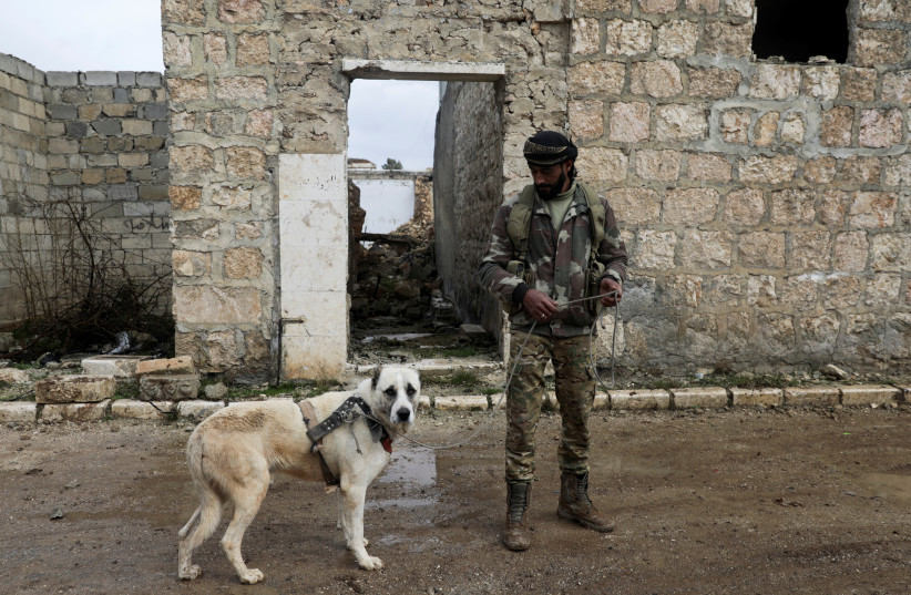  A Syrian rebel fighter walks with a dog in the town of Tadef, on a frontline between Russian-backed Syrian government forces and Turkey-backed Syrian rebel-held territory, in northern Syria March 3, 2022 (photo credit: REUTERS)