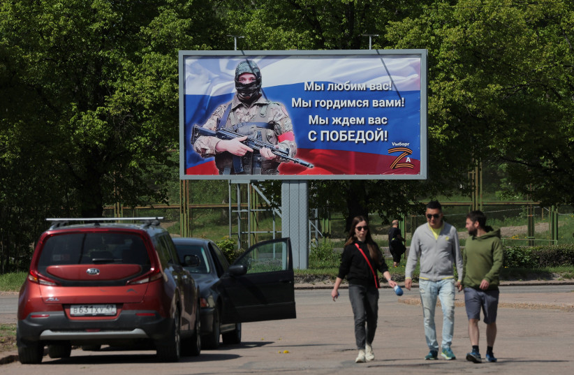  People walk near a banner in support of the Russian Army, in the town of Vyborg, Leningrad Region, Russia May 28, 2023 (photo credit: REUTERS/ANTON VAGANOV)