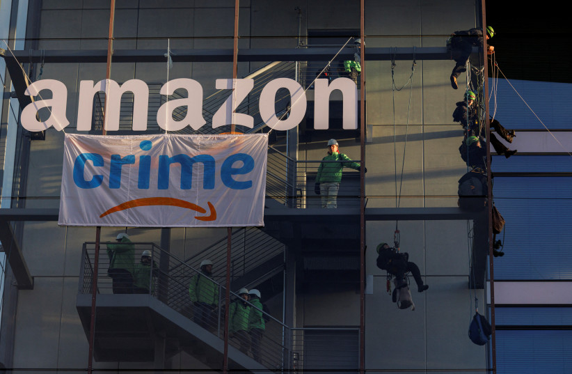 Activists of Greenpeace attach a banner reading 'crime', which looks like the 'Amazon prime' logo at the Amazon headquarters in Munich, Germany, November 25, 2022 (photo credit: REUTERS/Lukas Barth)