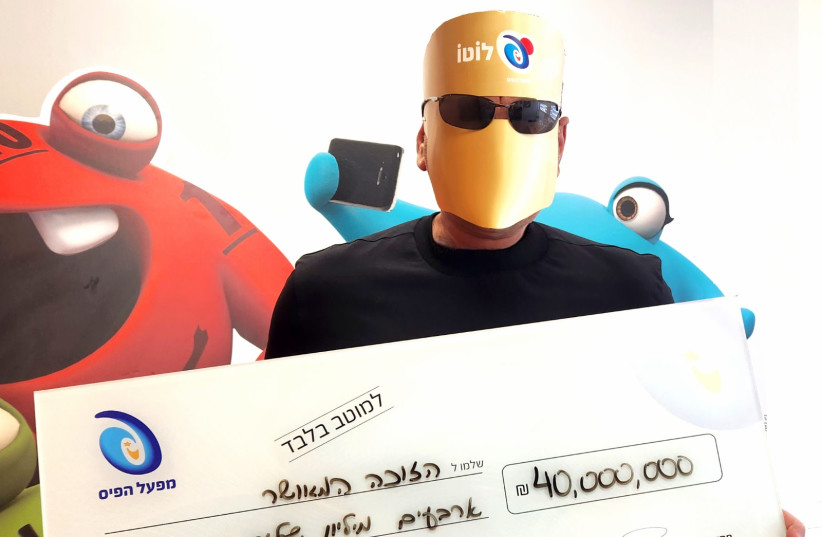  The winner of Mifal Hapayis' NIS 40 million jackpot is seen with his earnings on June 21, 2023 (photo credit: MIFAL HAPAYIS NATIONAL LOTTERY)